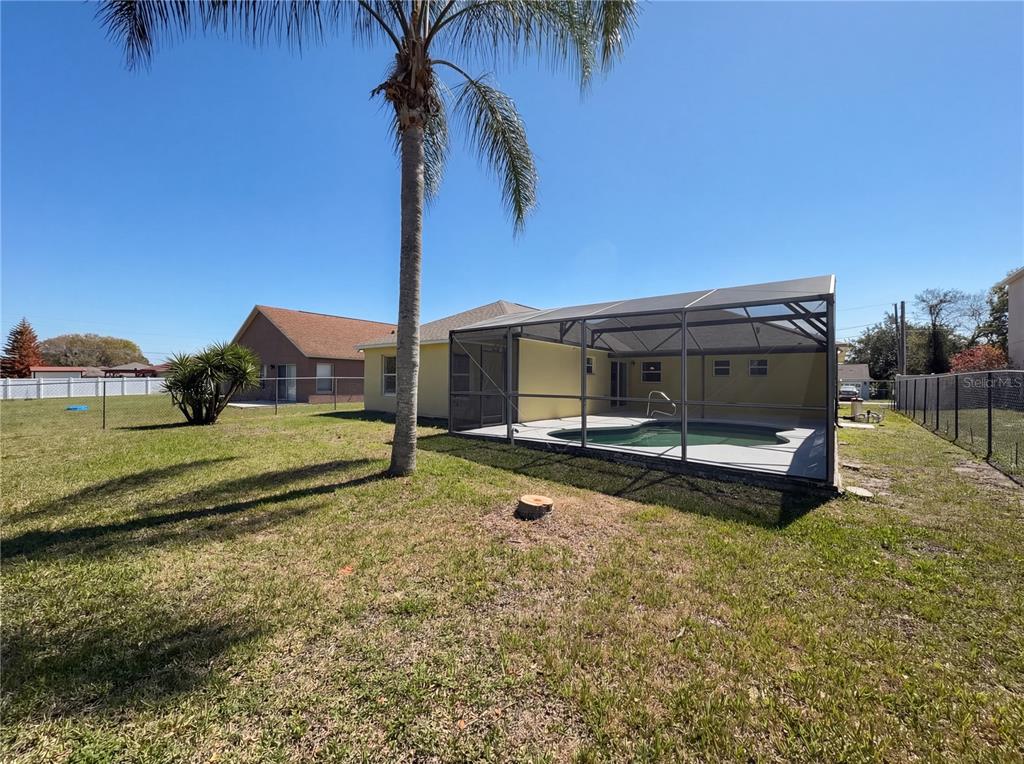A backyard view featuring a swimming pool enclosed by a screened lanai and a palm tree — 107 HERRING WAY, KISSIMMEE, FL