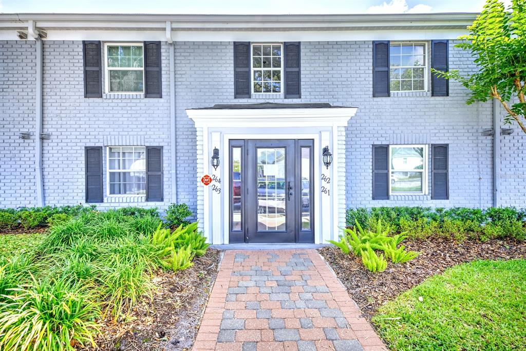 The exterior of a two-story brick apartment building features a central entrance with a walkway — 262 LEWFIELD CIRCLE UNIT 262, WINTER PARK, FL