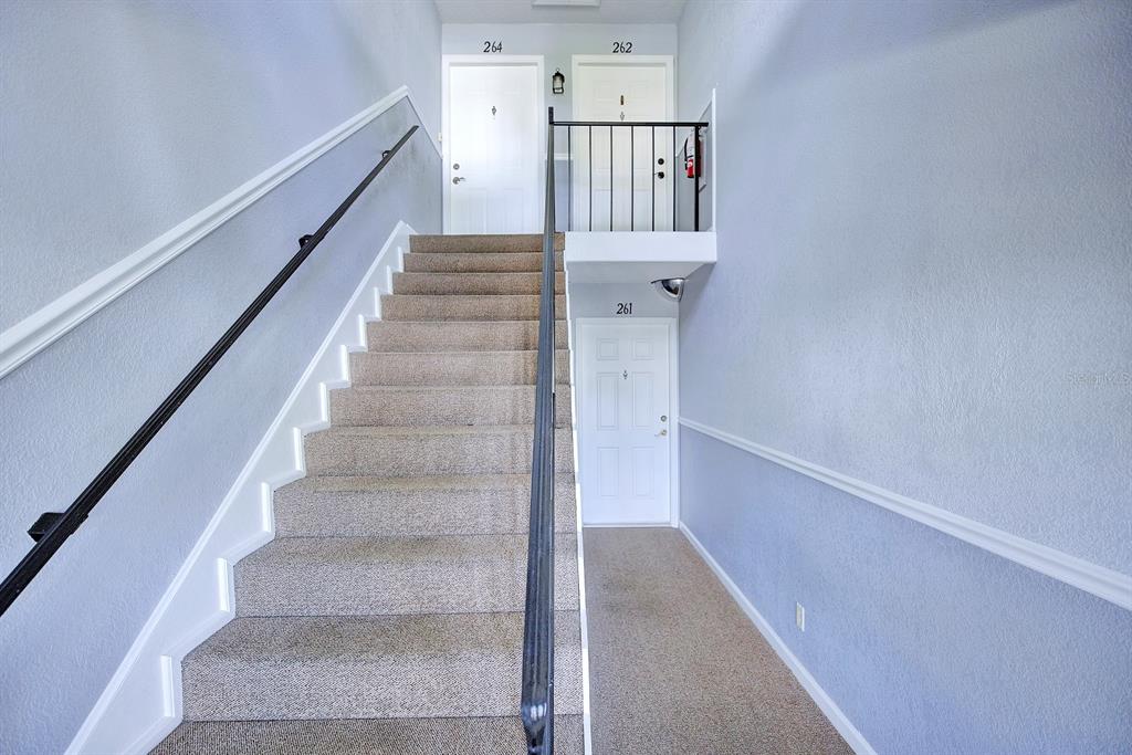 A carpeted staircase leads to an upper landing with two doors and one lower door — 262 LEWFIELD CIRCLE UNIT 262, WINTER PARK, FL