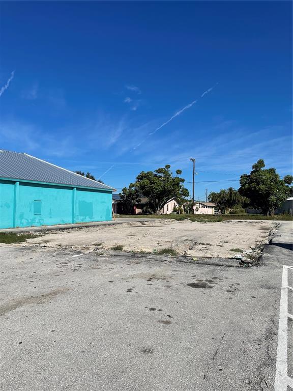 A vacant, cleared dirt lot sits adjacent to a turquoise building under a clear blue sky — 3782 TAMIAMI TRAIL UNIT B, PORT CHARLOTTE, FL