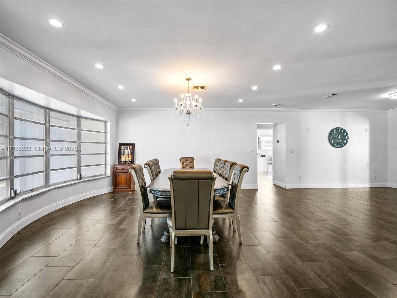 A dining room features a long table with chairs, a chandelier, and tile flooring — 3610 N 53rd Ave, Hollywood FL 33021, HOLLYWOOD, FL