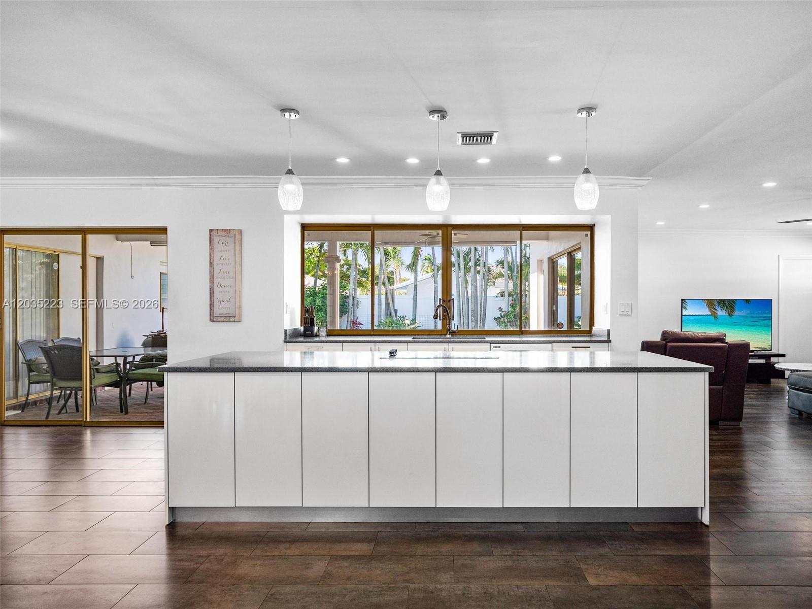 A modern kitchen features a large white island, dark wood flooring, and a large window — 3610 N 53rd Ave, Hollywood FL 33021, HOLLYWOOD, FL