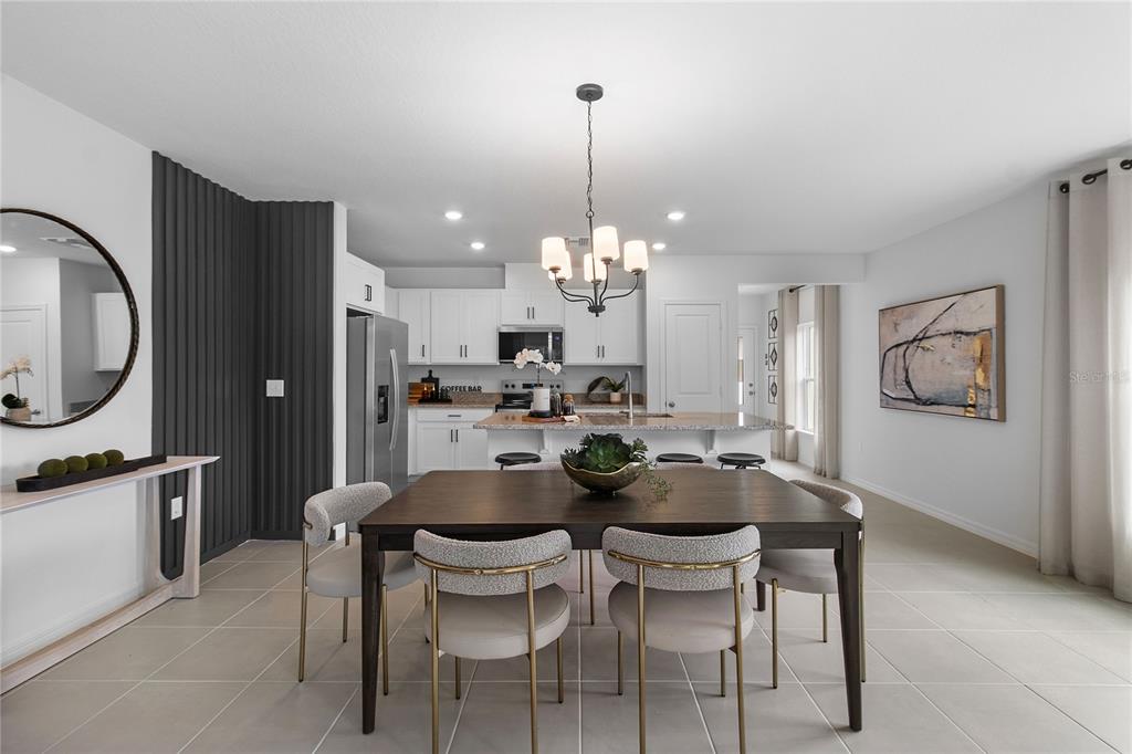 A dining area with a dark wood table and chairs opens to a white kitchen — 16639 LUMINARY, CLERMONT, FL
