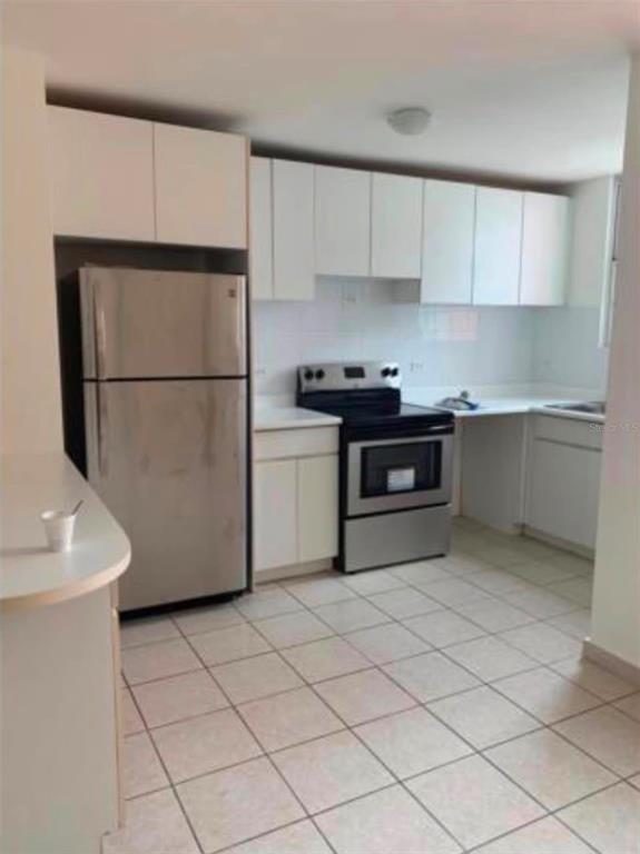 A kitchen features white cabinets, stainless steel appliances, and light-colored tile flooring — Apartments MONTESOL UNIT E-312, FAJARDO, PR