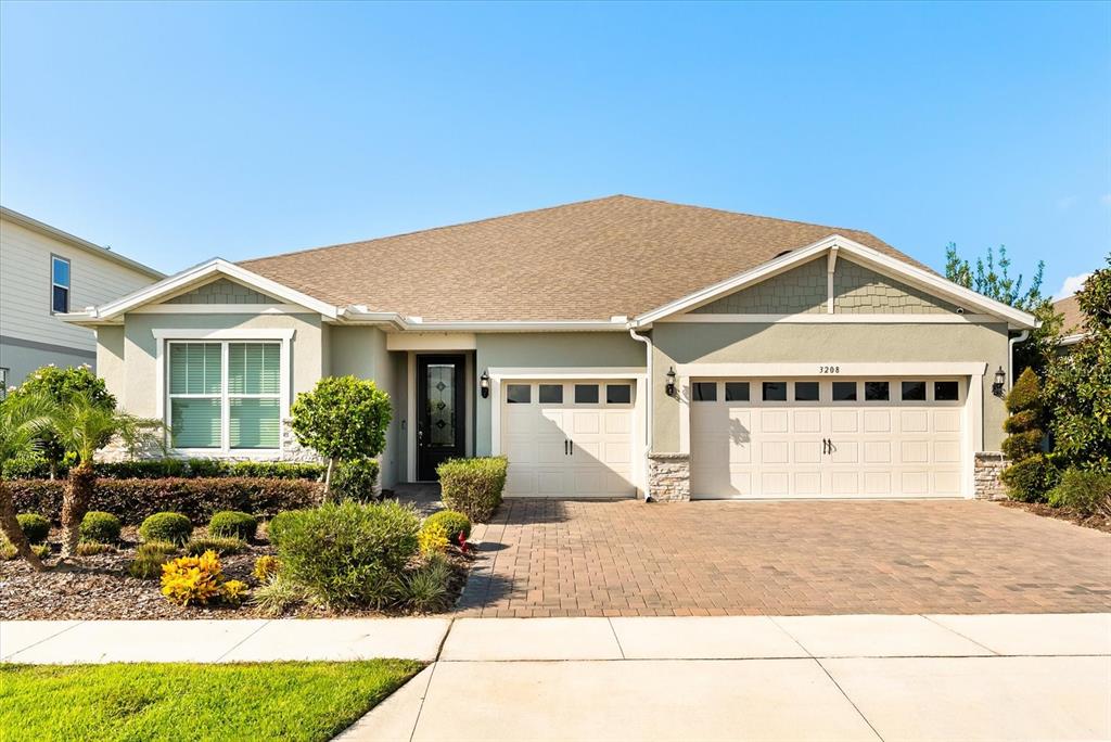 A single-story house with a light green exterior, a three-car garage, and a paved driveway — 3208 SAILING PIER AVENUE, WINTER GARDEN, FL