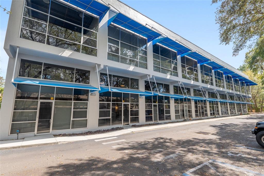 A two-story commercial building with blue awnings and large glass windows along a parking lot — 2515 SW 35TH PLACE UNIT 219, GAINESVILLE, FL