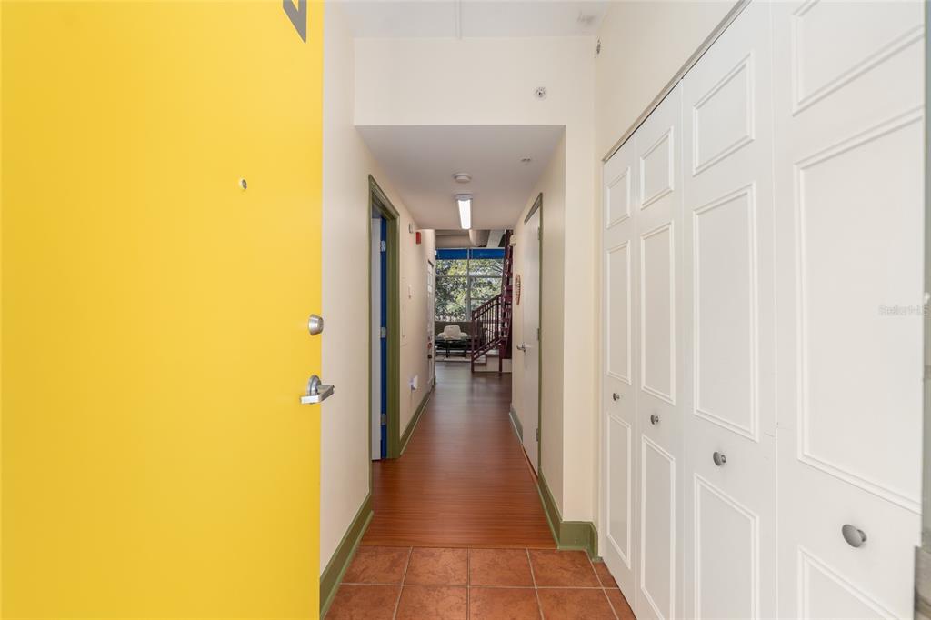 An entryway with a yellow door, tile flooring, and a hallway leading to a living area — 2515 SW 35TH PLACE UNIT 219, GAINESVILLE, FL