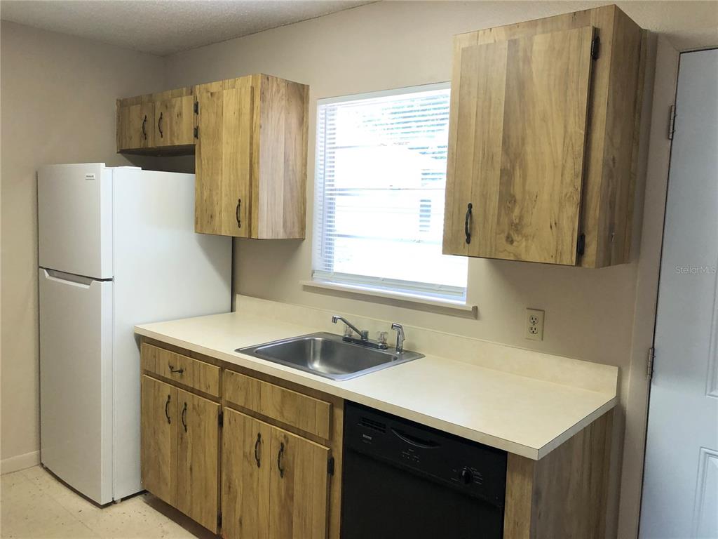 A kitchen features wood-grain cabinets, a white refrigerator, a stainless steel sink, and a dishwasher — 308 W CRESCENT DRIVE UNIT 2, LAKELAND, FL