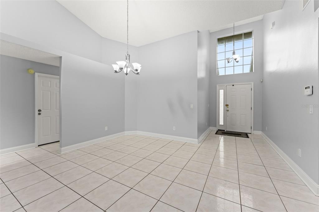 A high-ceilinged dining area features light gray walls, white trim, and large square floor tiles — 632 HERONS NEST COURT, ORLANDO, FL