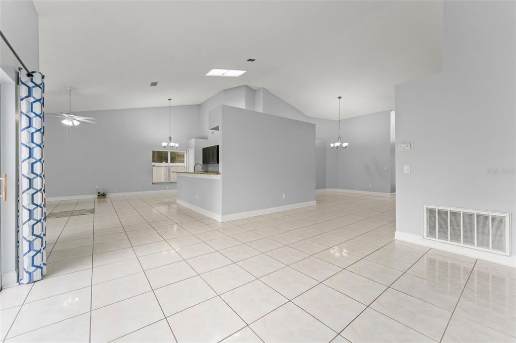 An open-concept living area features light-colored tile flooring, vaulted ceilings, and a central kitchen island — 632 HERONS NEST COURT, ORLANDO, FL