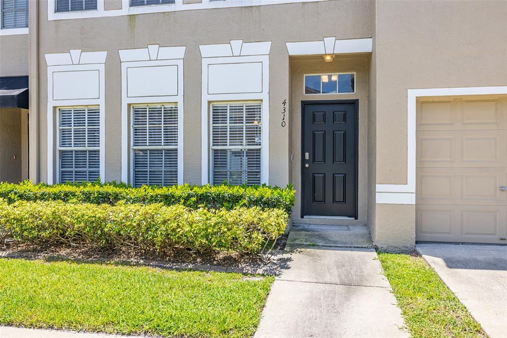 The exterior view shows a tan townhouse with a black front door and garage — 4310 FINCASTLE COURT, TAMPA, FL