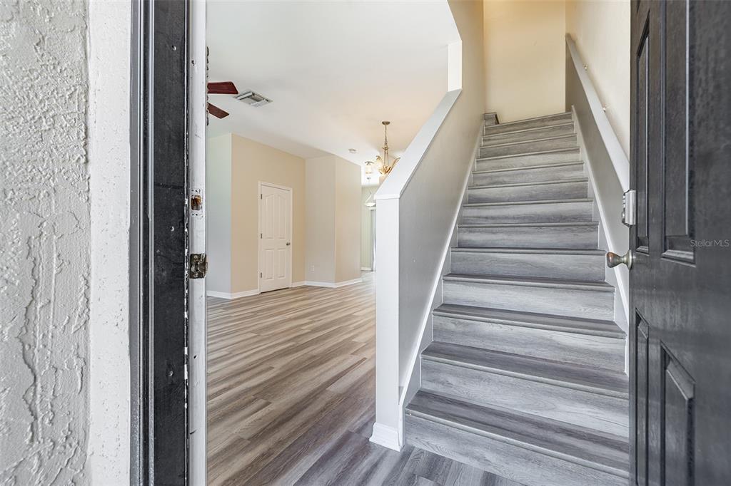 An entryway features a staircase with gray wood-look steps and light-colored flooring throughout — 4310 FINCASTLE COURT, TAMPA, FL