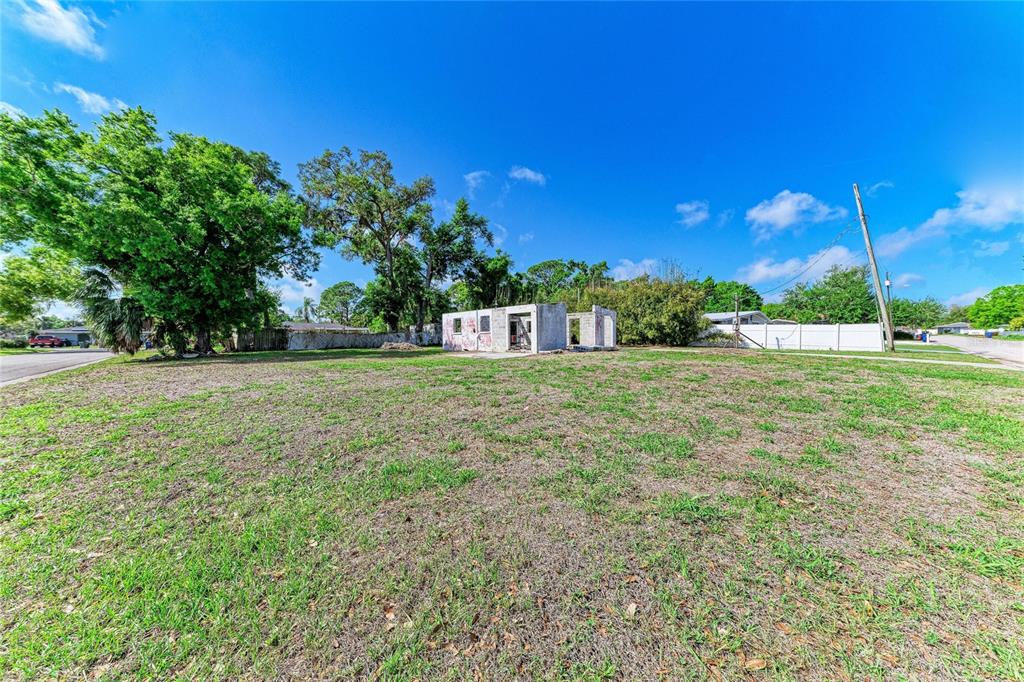 A vacant lot features a small, unfinished concrete block structure under a bright blue sky — 0 DOVER STREET, SARASOTA, FL