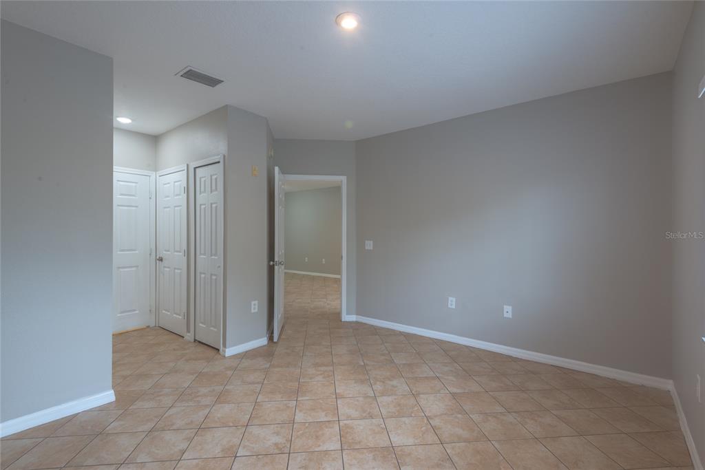 An empty room features beige tile flooring, gray walls, and several white interior doors — 6007 SKYDALE WAY UNIT 201, RIVERVIEW, FL