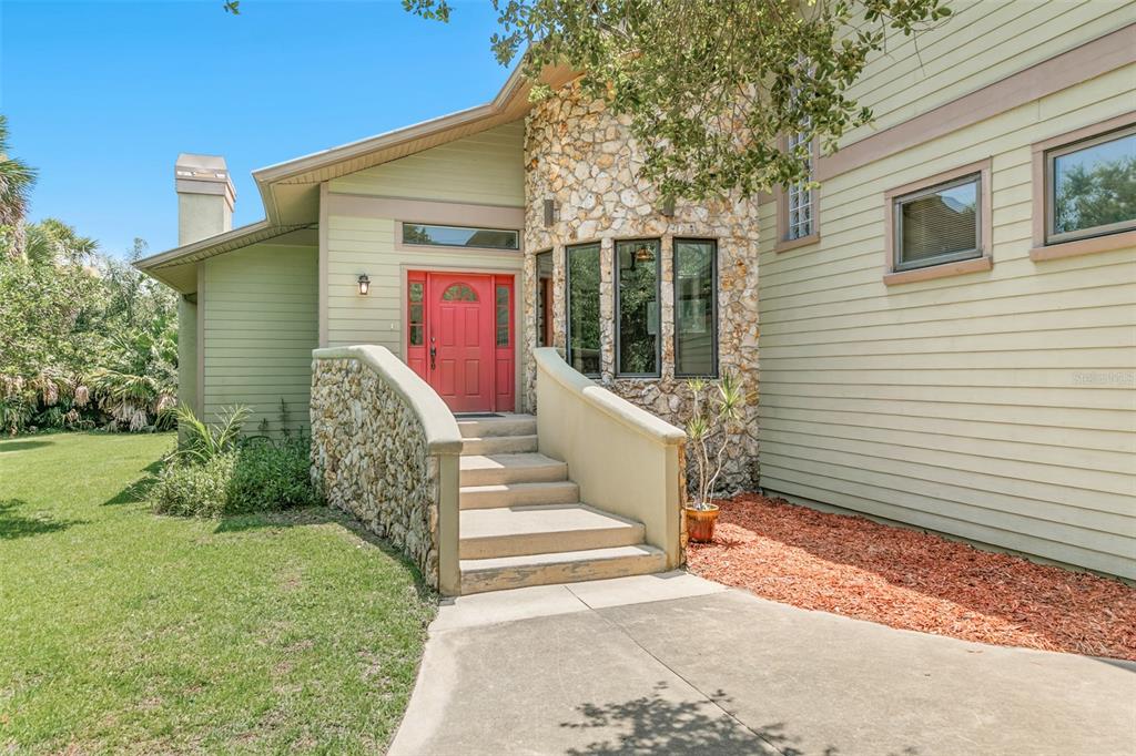 A house exterior with light green siding, a stone facade, and a bright red front door — 59 BEACH STREET, PONCE INLET, FL