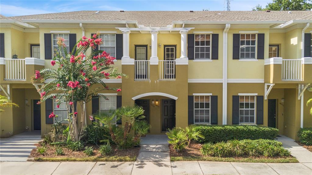 A two-story townhouse exterior features yellow stucco walls, dark shutters, and a small front garden — 14017 CITRUS CREST CIRCLE, TAMPA, FL