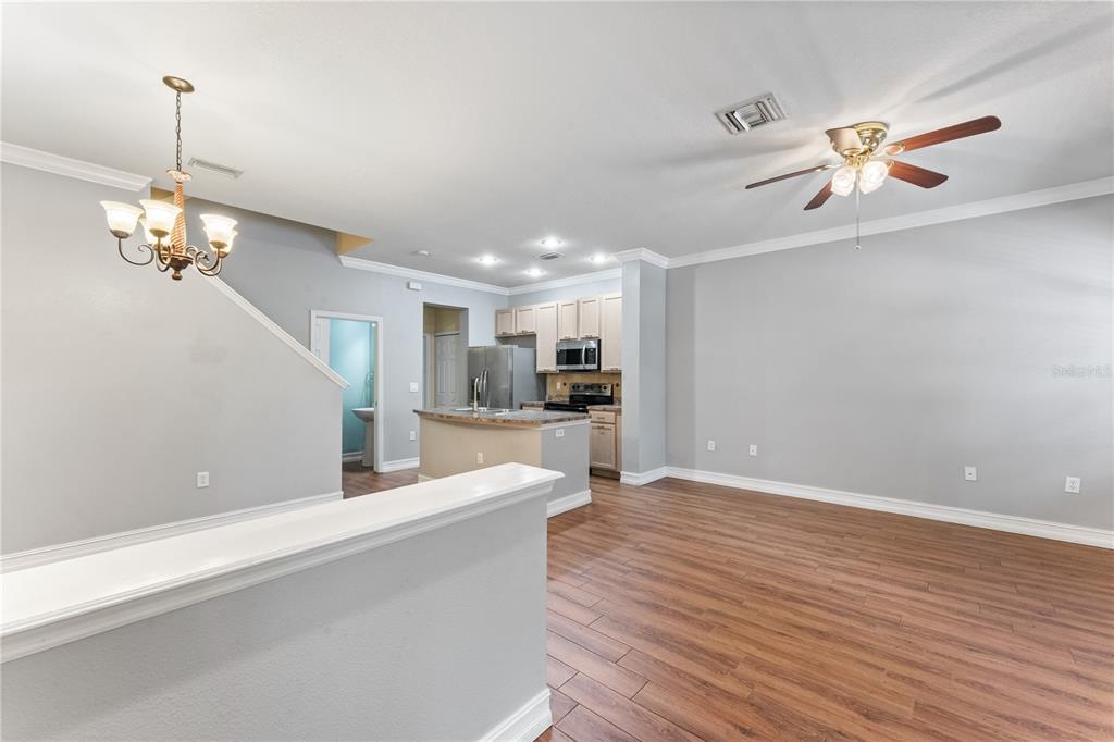 An open-concept living area features wood-look flooring, a kitchen with light cabinets, and a chandelier — 14017 CITRUS CREST CIRCLE, TAMPA, FL