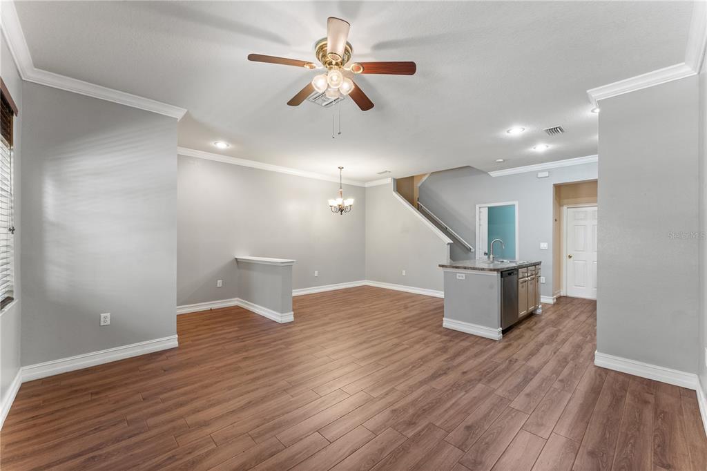 An open-concept living and dining area features wood-look flooring, a kitchen island, and stairs — 14017 CITRUS CREST CIRCLE, TAMPA, FL