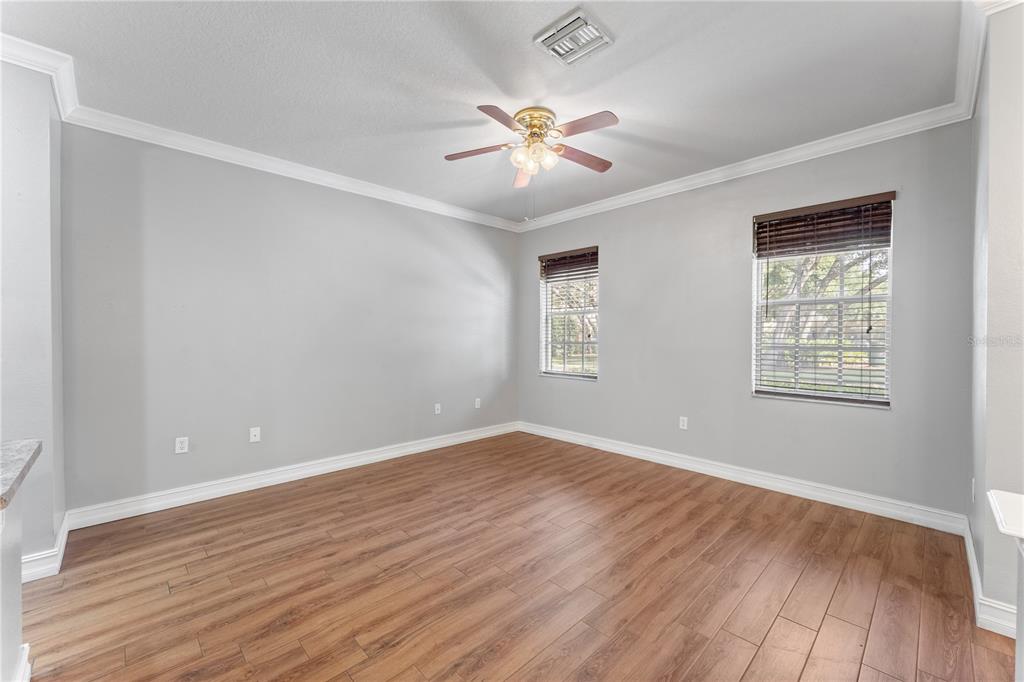 An empty room with light gray walls, wood-look flooring, two windows, and a ceiling fan — 14017 CITRUS CREST CIRCLE, TAMPA, FL
