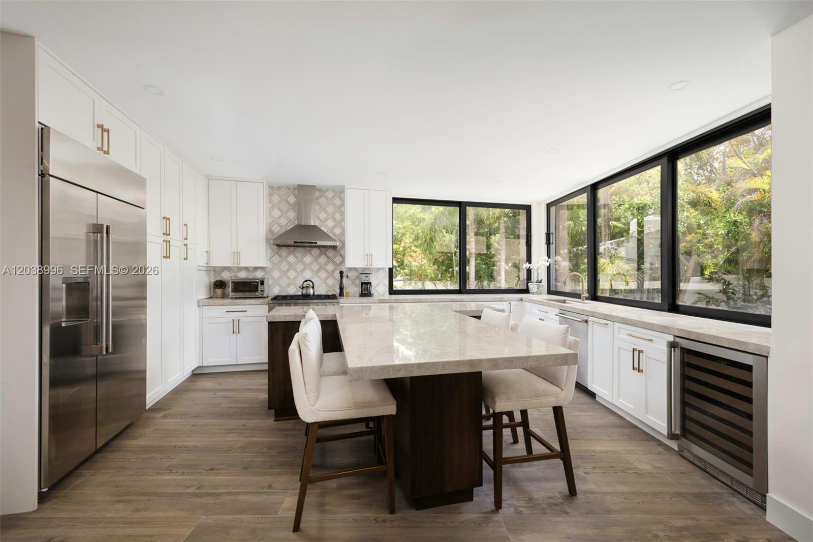 A modern kitchen features white cabinetry, a dark wood island, stone countertops, and large windows — 3303 Halissee St, Coconut Grove FL 33133, COCONUT GROVE, FL