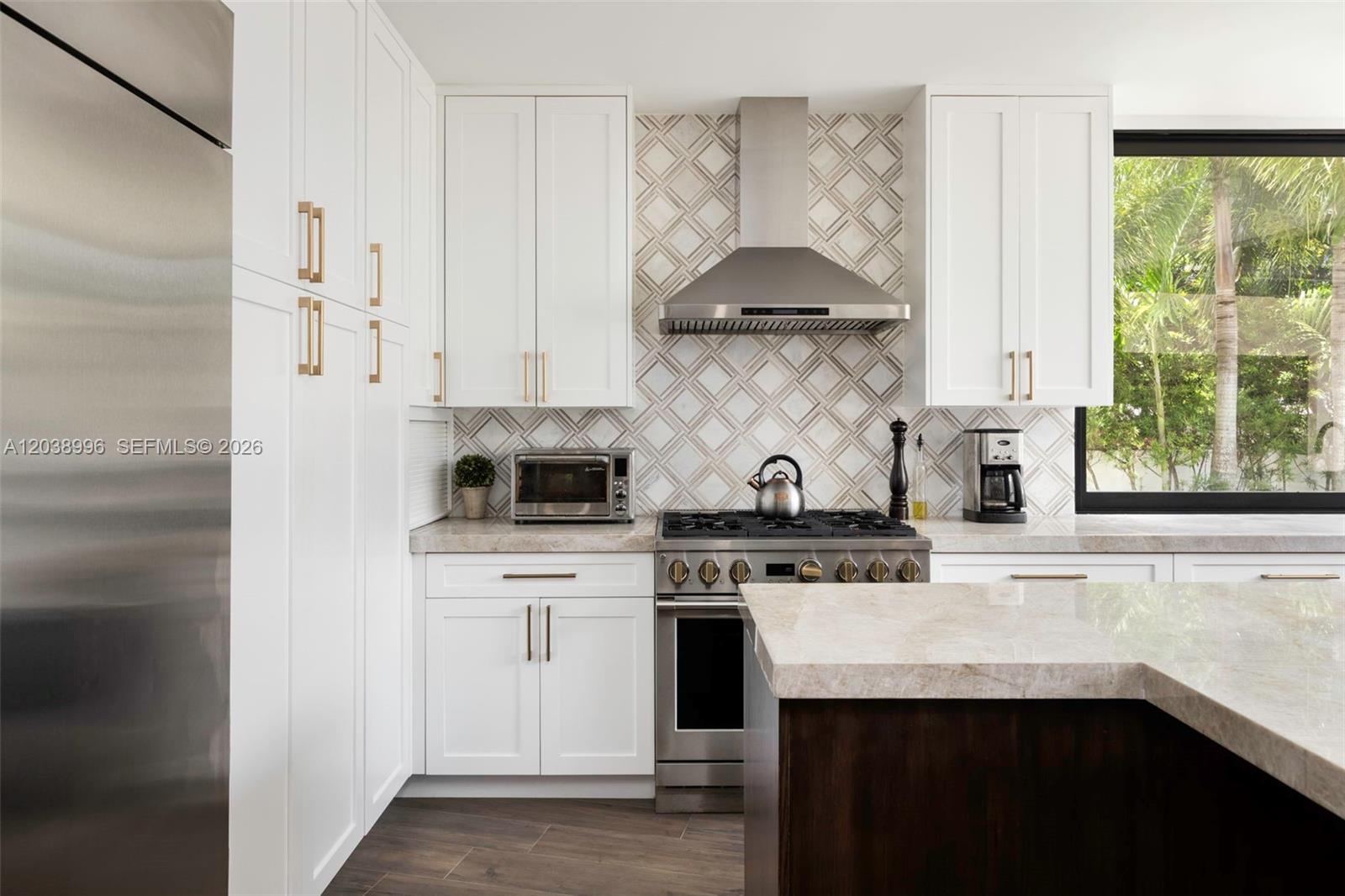 A modern kitchen features white cabinets, stainless steel appliances, a patterned backsplash, and stone countertops — 3303 Halissee St, Coconut Grove FL 33133, COCONUT GROVE, FL