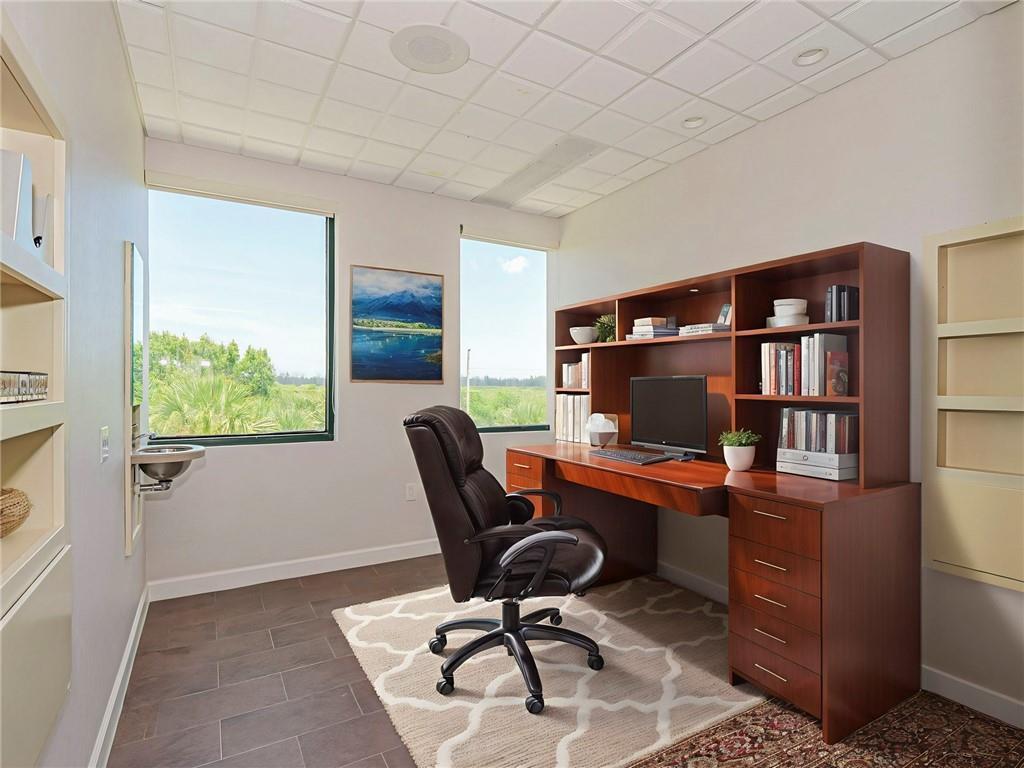 A home office with a wooden desk, a rolling chair, a rug, and a wall-mounted sink — 3755 7th Terrace, Vero Beach FL 32960, VERO BEACH, FL