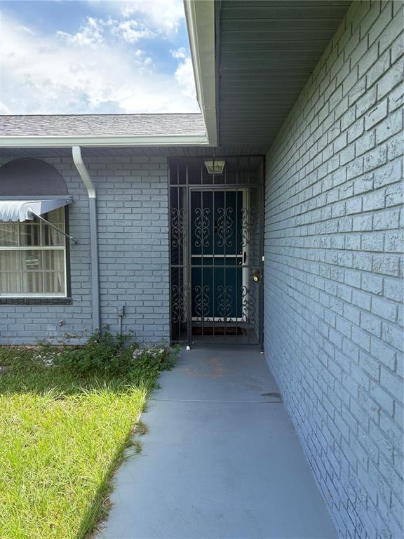 A gray brick house exterior features a front door with a black decorative security gate — 10 BAHIA WAY, OCALA, FL