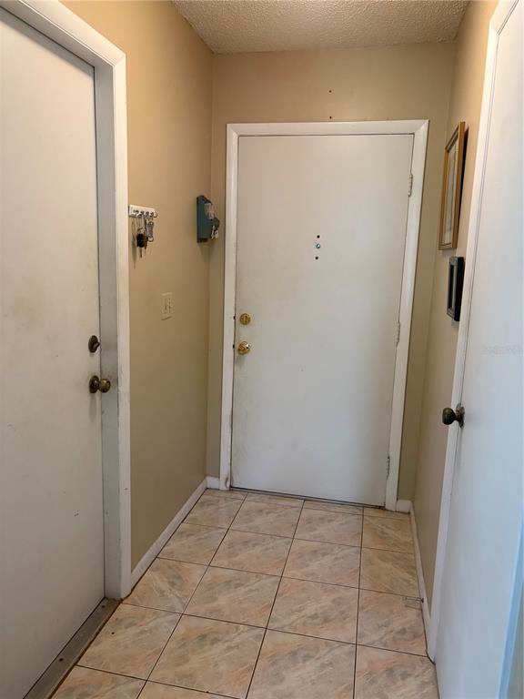 A small entryway features tiled flooring, beige walls, and three white doors — 10 BAHIA WAY, OCALA, FL