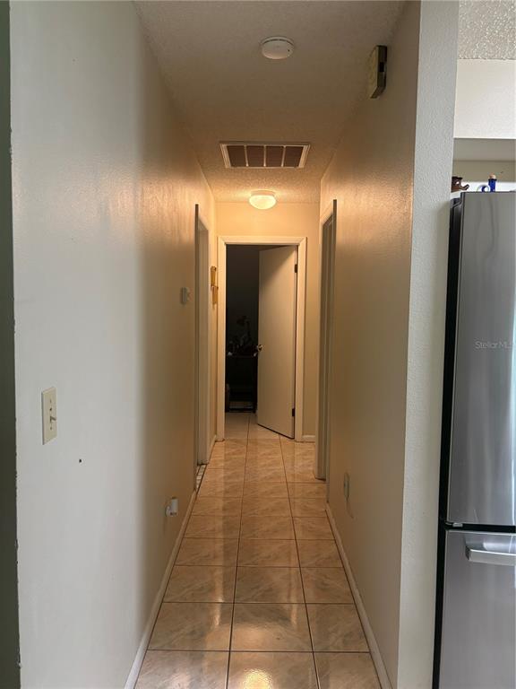 A narrow hallway with light-colored tile flooring leads to a doorway at the end — 10 BAHIA WAY, OCALA, FL
