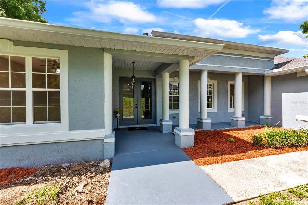 The exterior of a gray house features a covered entryway with white columns — 36510 SAINT JOE ROAD, DADE CITY, FL