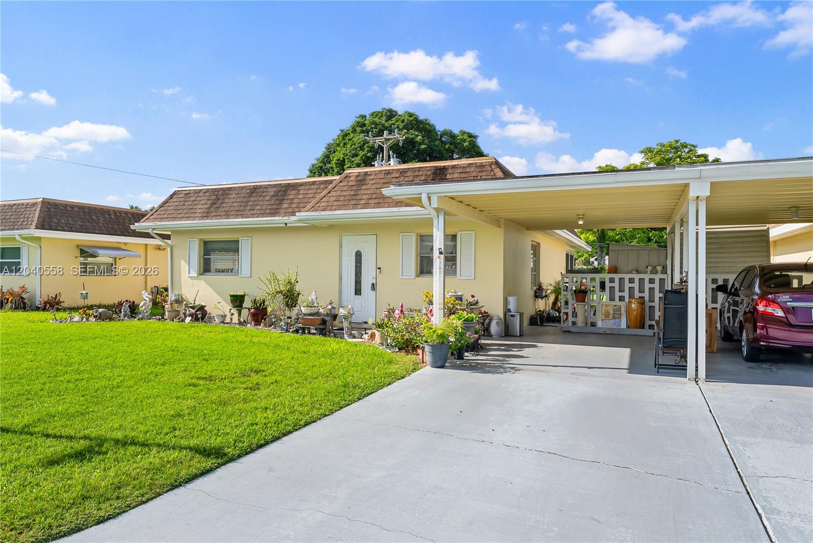 A yellow single-story house features a front lawn, a concrete driveway, and an attached carport — 2208 Gardenia Way, Lehigh Acres FL 33936, LEHIGH ACRES, FL