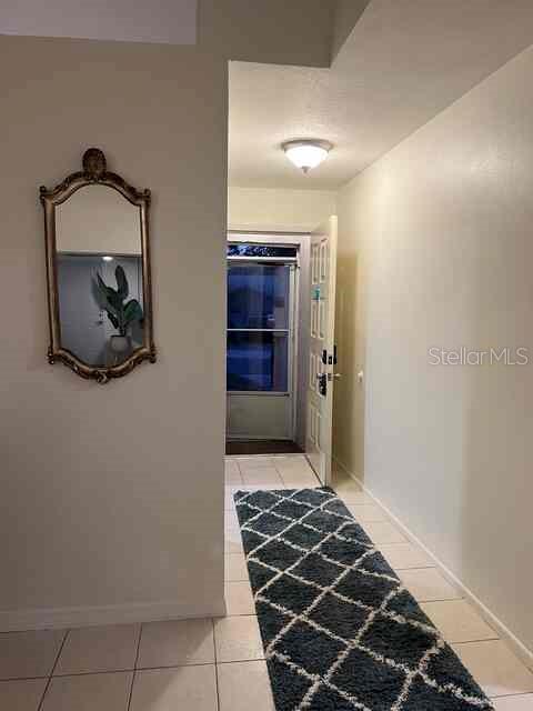 An entryway features a tiled floor, a decorative wall mirror, and a rug leading outdoors — 3761 LAKE SHORE DRIVE, PALM HARBOR, FL