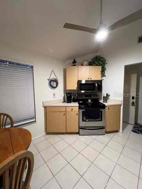 A kitchen features light wood cabinets, stainless steel appliances, and white tile flooring — 3761 LAKE SHORE DRIVE, PALM HARBOR, FL