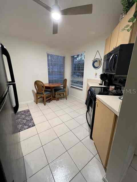 A kitchen with light wood cabinets, white tile floors, and a small dining area — 3761 LAKE SHORE DRIVE, PALM HARBOR, FL