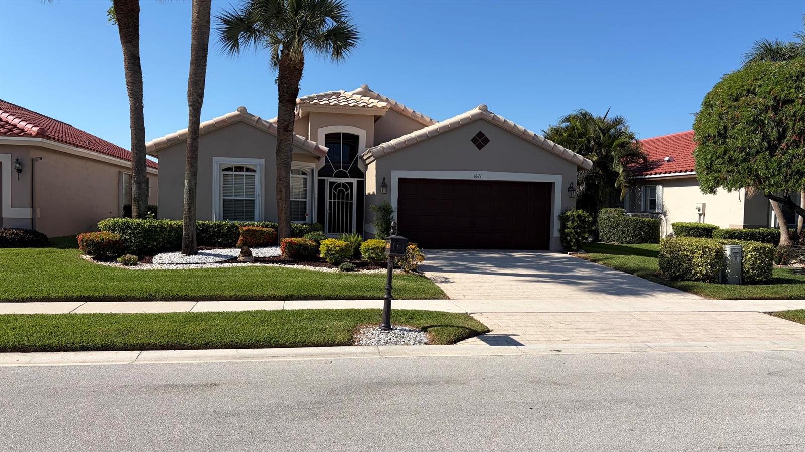 A single-story suburban house features a beige stucco exterior, a tiled roof, and a driveway — 6671 Maybrook Road, Boynton Beach FL 33437, BOYNTON BEACH, FL