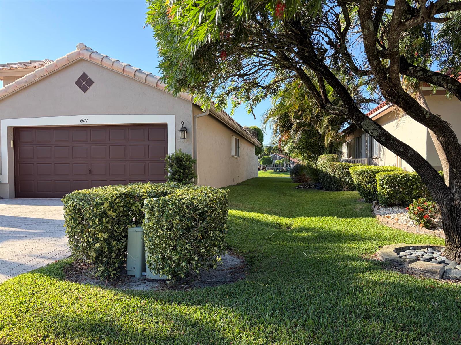 A beige house with a brown garage door and a green lawn with landscaping — 6671 Maybrook Road, Boynton Beach FL 33437, BOYNTON BEACH, FL