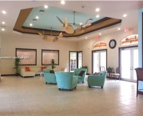 A spacious lobby features a tray ceiling with ceiling fans and light blue armchairs — 5580 NW 61st St # 602, Coconut Creek FL 33073, COCONUT CREEK, FL
