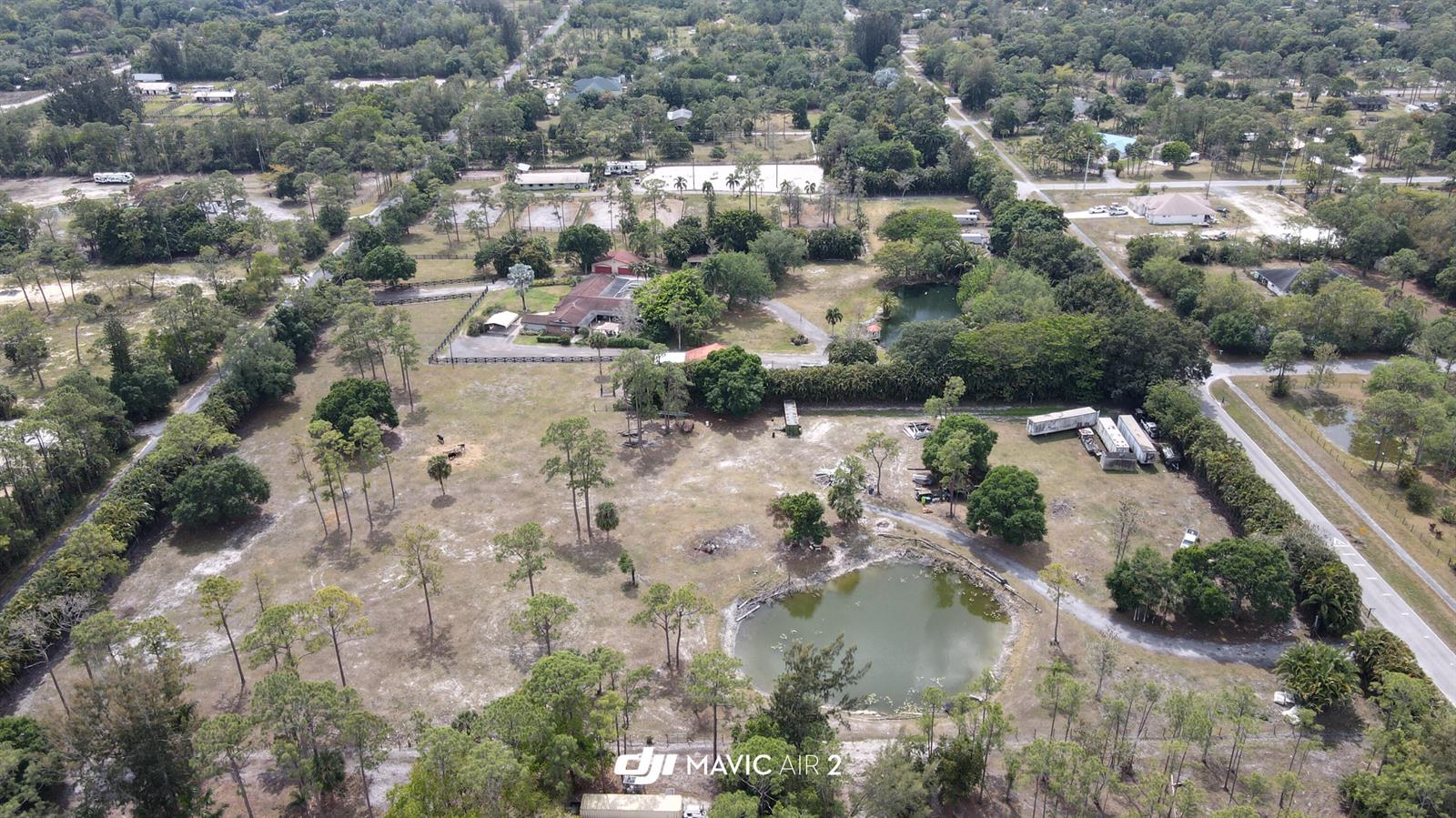 An aerial view shows a rural property with a house, a pond, and fenced pastures — 3547 161st Terrace N, FL 33470, FL