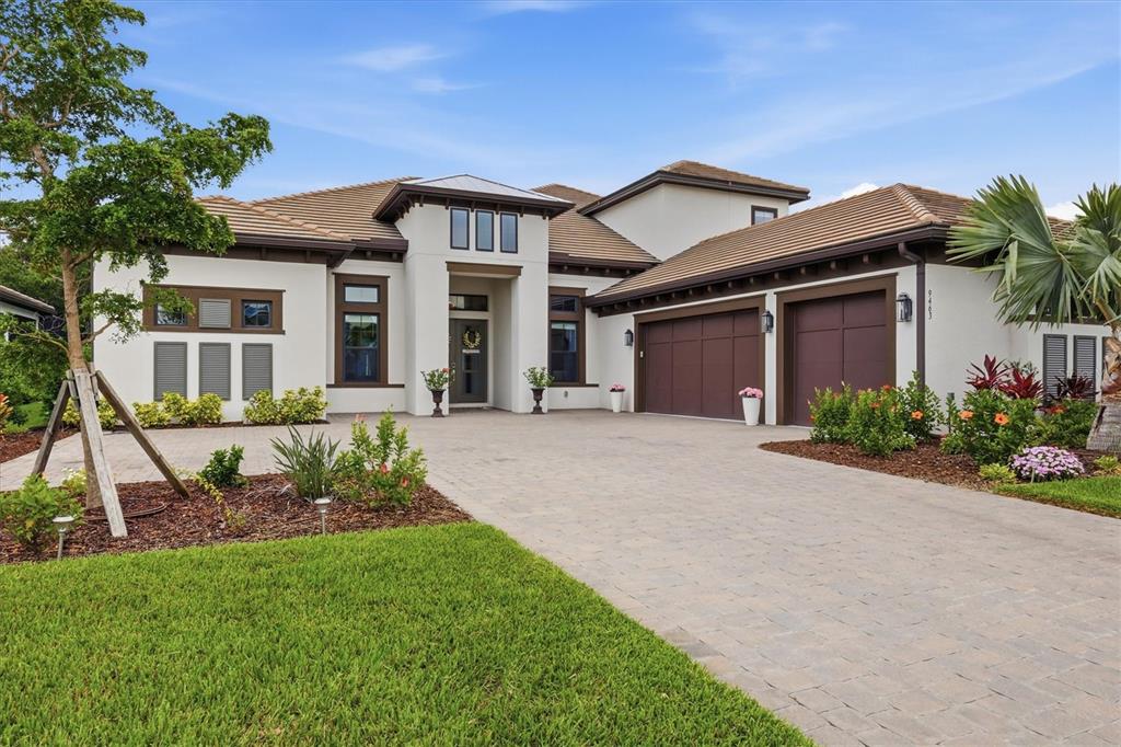 A single-story house with a white stucco exterior, brown trim, and a paved driveway — 9463 TEQUILA SUNRISE DRIVE, SARASOTA, FL