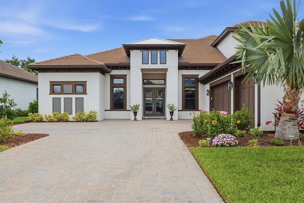 A single-story house with a paved driveway, white stucco walls, and brown trim — 9463 TEQUILA SUNRISE DRIVE, SARASOTA, FL