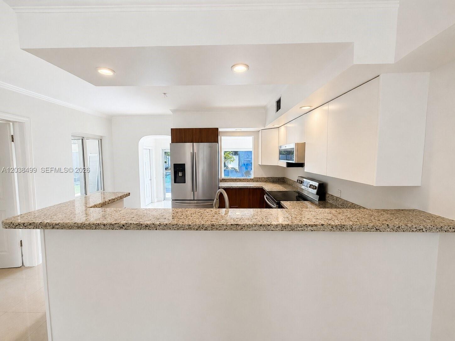 A kitchen features granite countertops, white cabinetry, stainless steel appliances, and recessed lighting — 1919 Sherman St, Hollywood FL 33020, HOLLYWOOD, FL