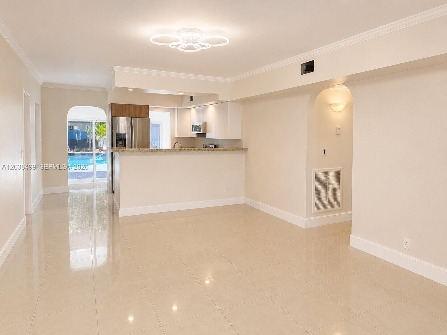An open-concept living area features light tile flooring, a kitchen with stainless appliances, and an archway — 1919 Sherman St, Hollywood FL 33020, HOLLYWOOD, FL