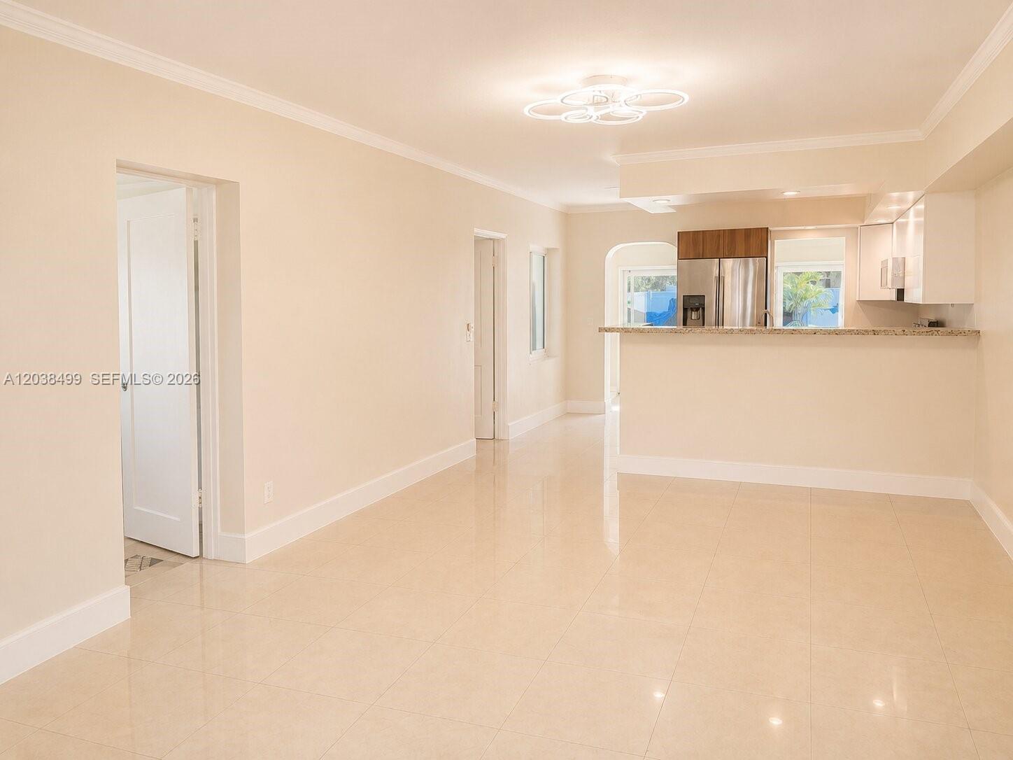 A bright, open-concept living and dining area features light-colored tile flooring and a kitchen pass-through — 1919 Sherman St, Hollywood FL 33020, HOLLYWOOD, FL