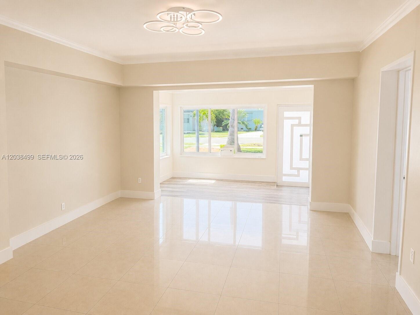 A bright, empty room features light-colored tile flooring, beige walls, and a large windowed alcove — 1919 Sherman St, Hollywood FL 33020, HOLLYWOOD, FL