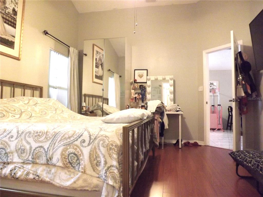 A bedroom features a bed with a paisley comforter, wood flooring, and a vanity area — 216 SANDHILL CRANE RUN, ORLANDO, FL