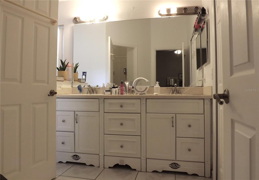 A bathroom features a double vanity with white cabinets, a large mirror, and tiled flooring — 216 SANDHILL CRANE RUN, ORLANDO, FL