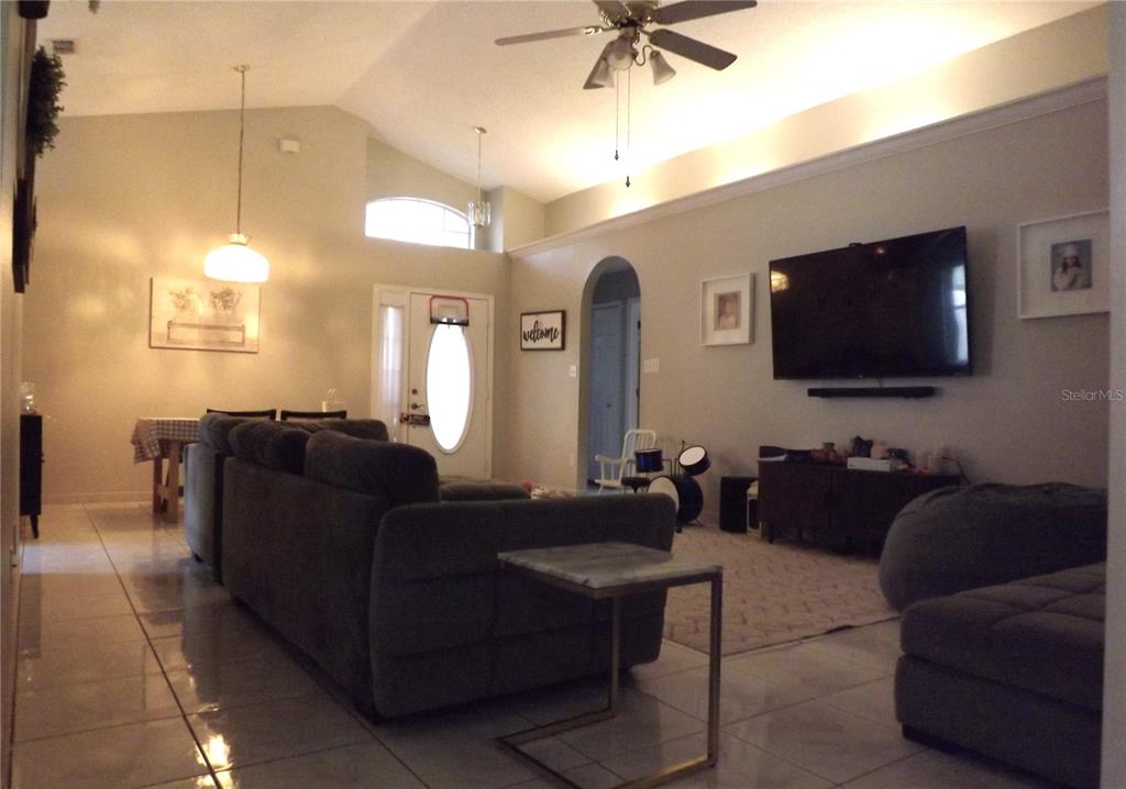 A living room features a large sectional sofa, a wall-mounted television, and tile flooring — 216 SANDHILL CRANE RUN, ORLANDO, FL