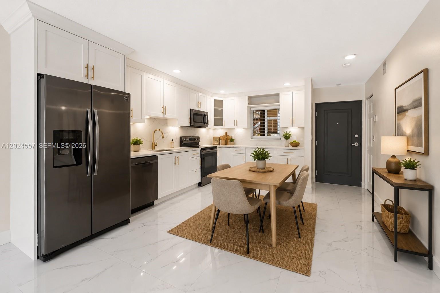 A modern kitchen features white cabinetry, stainless steel appliances, and a dining table on tile — 7920 Camino Real # 109, Miami FL 33143, MIAMI, FL