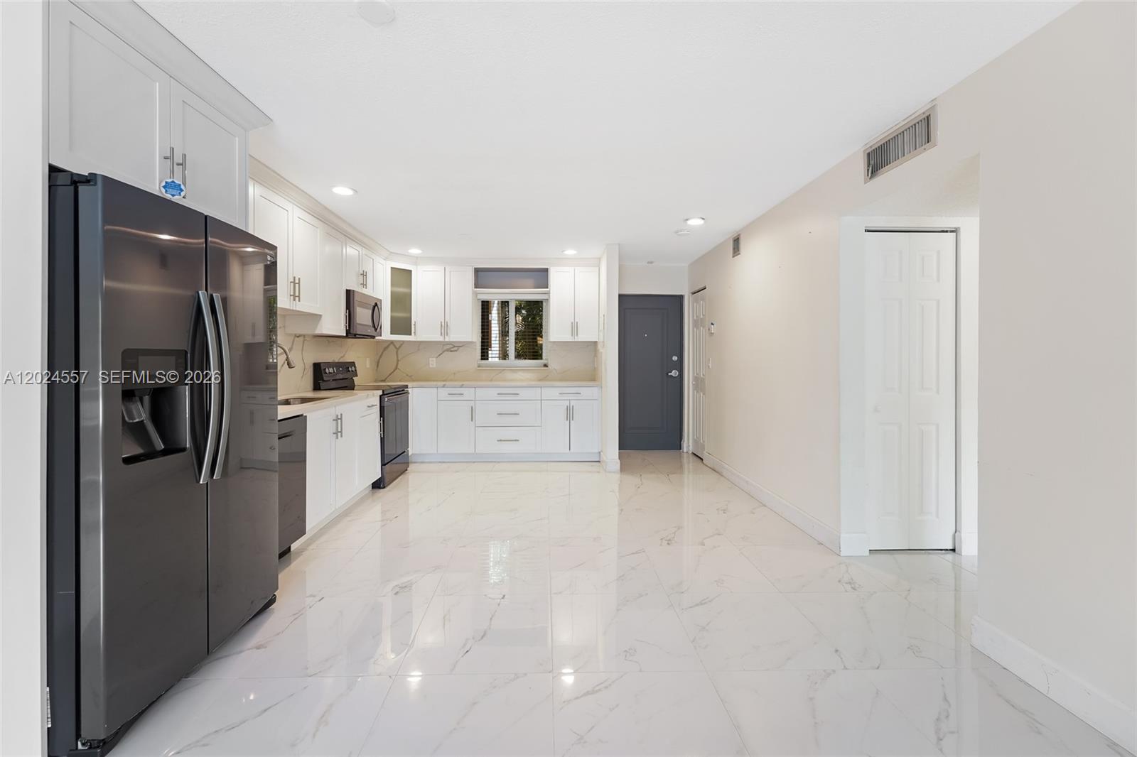 A kitchen features white cabinets, stainless steel appliances, and white marble-patterned tile flooring — 7920 Camino Real # 109, Miami FL 33143, MIAMI, FL