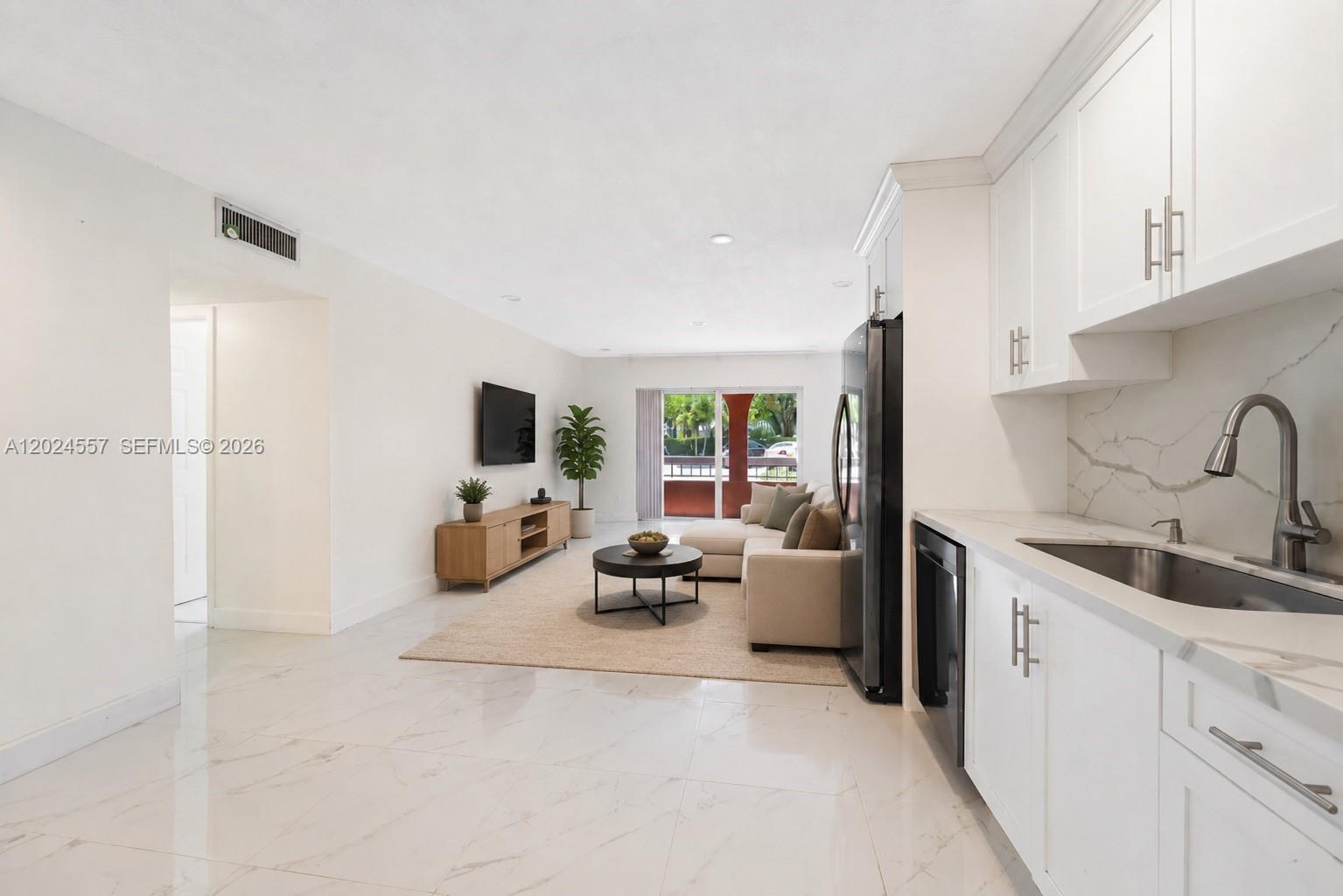 A bright open-concept living area features white marble floors, a kitchen, and a balcony view — 7920 Camino Real # 109, Miami FL 33143, MIAMI, FL